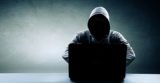 Hacker: Mann mit Kapuze vor Laptop