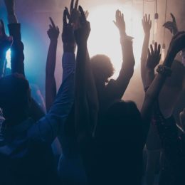Menschen die auf einer Party mit den Händen hoch feiern