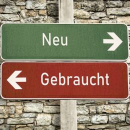 Grünes Schild mit der Aufschrift „Neu" und einem Pfeil nach rechts, rotes Schild mit der Aufschrift „Gebraucht" und einem Pfeil nach links