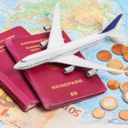 Flugzeug auf Reisepass, Weltkarte und Geld