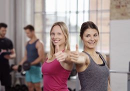 zwei Frauen im Fitnessstudio die Daumen hoch zeigen