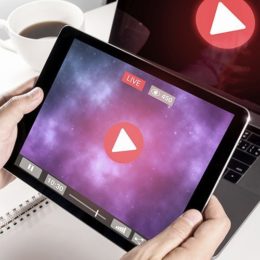 Mann hält Tablet mit Live Stream Symbol