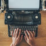 Mann tippt auf einer alten Schreibmaschine