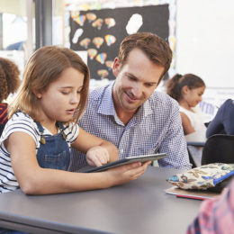 Lehrer und Schülerin nutzen Tablet im Klassenzimmer