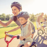 Mutter bringt Kind das Fahrradfahren mit Helm bei