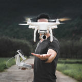 Mann mit abhebender Drohne in der Hand