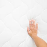 weibliche Hand auf weißer Matratze