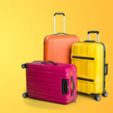 bunte Koffer stehen vor einem gelben Hintergrund