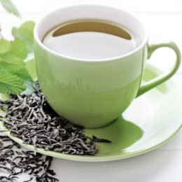 Tasse mit grünem Tee neben Gewürzen