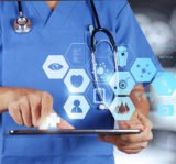 Arzt mit blauem Kittel und Stetoskop mit Tablet in der Hand