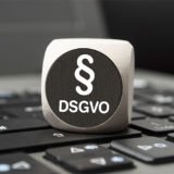 Würfel mit Paragraphenzeichen und DSGVO Gesetzesbezeichnung auf Tastatur