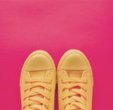 Gelbe Sneaker vor einem pinken Hintergrund