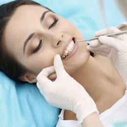 Frau beim Zahnarztbesuch mit schönen weißen Zähnen