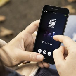 Smartphone mit Radio-App in den Händen einer Frau