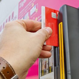 Hand zieht Bankkarte durch den Schlitz eines Zigarettenautomats
