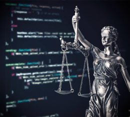 Justizia-Statue vor einem PC-Bildschirm