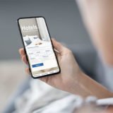 Eine Hand hält ein Smartphone mit einer Hotel-App