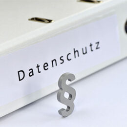 weißer Ordner auf dem Datenschutz steht mit Paragraphenzeichen im Vordergrund