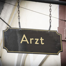 Schwarzes Schild mit goldener Aufschrift 'Arzt'
