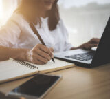 Frau am Laptop mit einem Stift