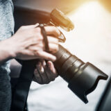 Kamera in Händen von Fotografen, im Hintergrund helles Licht