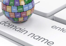Bunte Weltkugel mit Top-Level Domains auf Taste von Tastatur mit Aufschrift domain name