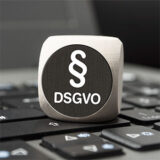 Würfel mit DSGVO-Aufschrift und Paragraphenzeichen auf einer Tastatur