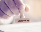 Man hält Stempel mit Mahnungsaufschrift in der Hand