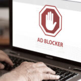 Mann tippt auf Laptop mit Adblock Zeichen