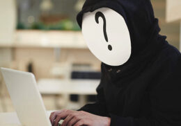 Person mit einem Fragezeichen im Gesicht tippt auf einem Laptop