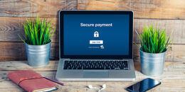 Text "Secure Payment" und Schloss auf Laptopbildschirm, der auf einem Schreibtisch steht.