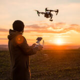 Mann mit Drohne im Sonnenuntergang