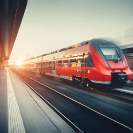 Roter Zug, der in einen Bahnhof einfährt bei Sonnenuntergang