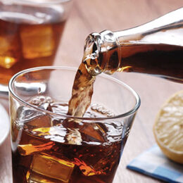 Cola wird in ein Glas mit Eiswürfeln eingeschenkt