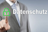 Mann im Anzug drückt mit dem Finger auf ein grünes Schloss vor dem Schriftzug "Datenschutz"