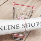 Zeitschrift mit Aufschrift Onlineshopping in kleinem Einkaufswagen
