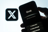 X Label im Hintergrund, KI-Chatbot Grok auf Handy im Vordergrund